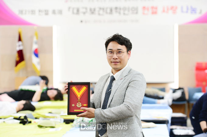 대구보건대학교 방사선과 김영재 교수가 대한적십자사로부터 받은 헌혈 유공장 금장을 들고 기념촬영을 하고 있다. (사진=대구보건대 제공)