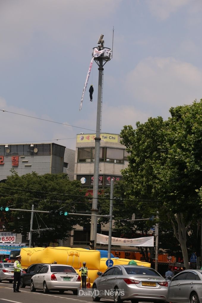대구 도심 영대네거리에서 한 남성이 CCTV 거치대에 올라 고공시위를 벌이고 있다. (사진=이준호 기자)
