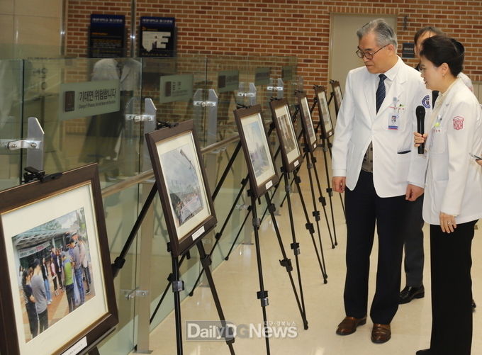 김권배 동산의료원장(왼쪽)과 김진희 동산의료선교복지회장(오른쪽)이 전시된 사진을 둘러보고 있다. (사진=계명대 동산의료원 제공)