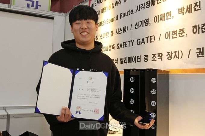 대상을 수상한 AI전자공학전공 ‘각자 따로’ 팀의 윤명하 학생이 출품작 앞에서 상장을 들고 기뻐하고 있다.