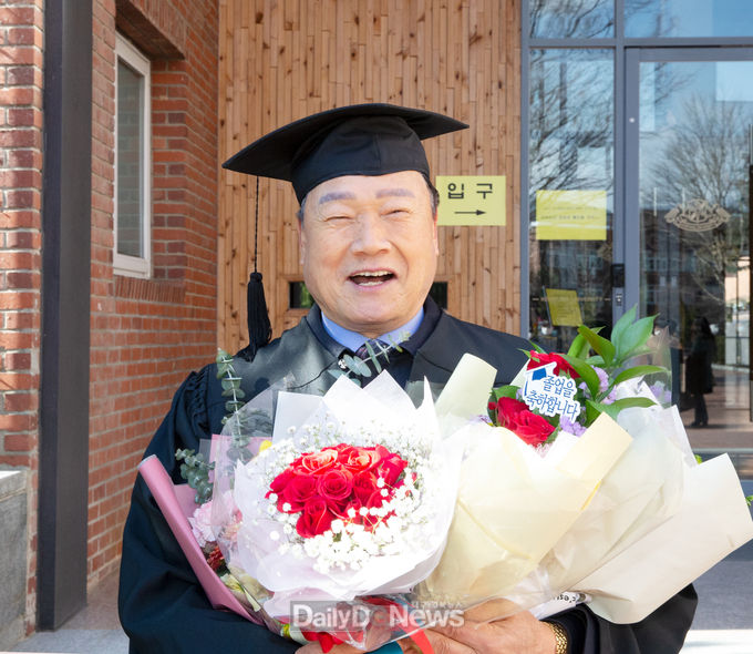 신현문씨가 2월 18일 계명대학교 학위 수여식에서 꽃다발을 안고 기념촬영을 하고 있다.