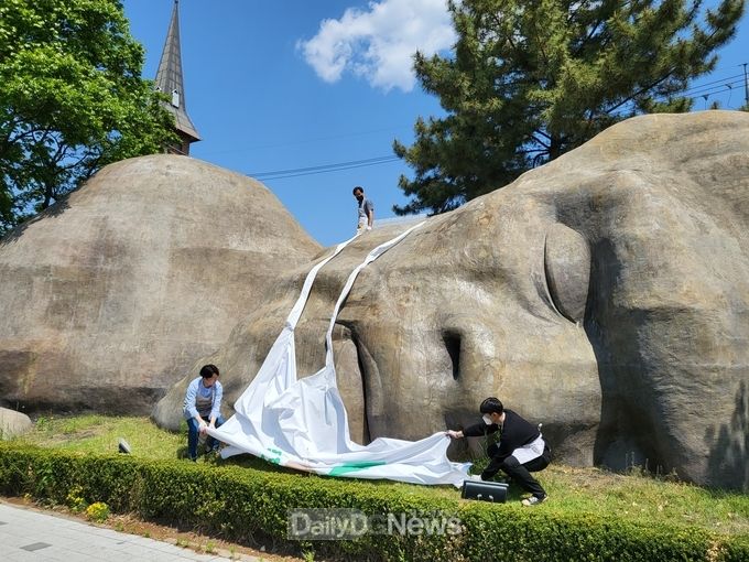 대구 달서구가 2일 코로나19 상황에서 완전히 벗어나길 기원하면서 거대원시인의 마스크를 벗기는 퍼포먼스를 진행하고 있다. (사진=달서구 제공)