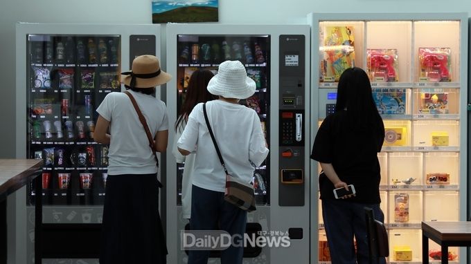 관람객들이 무인편의점 자판기에서 물건을 구입하고 있다