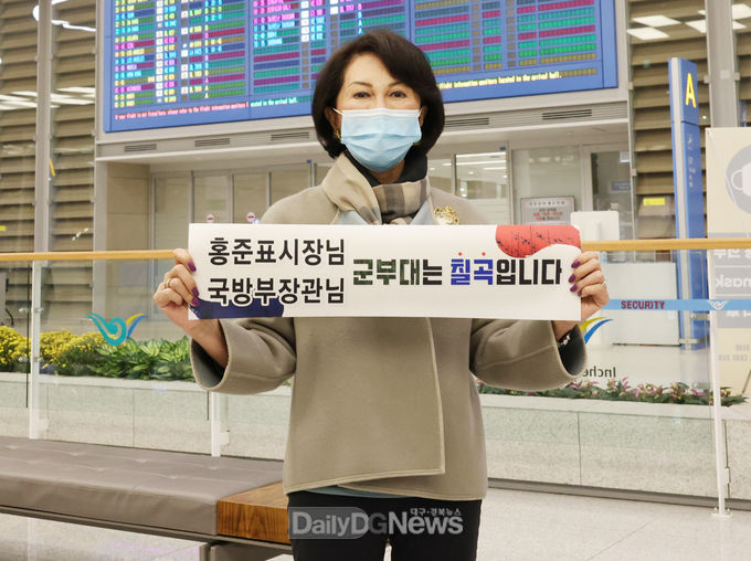 칠곡군 제공) 백남희 여사가 10월 24일 인천국제공항에서“馬은 제주도, 軍부대는 칠곡군”,“홍준표 시장님, 국방부 장관님 군부대는 칠곡군입니다.”라고 적힌 현수막으로 칠곡군 군부대 유치를 응원하고 있다.