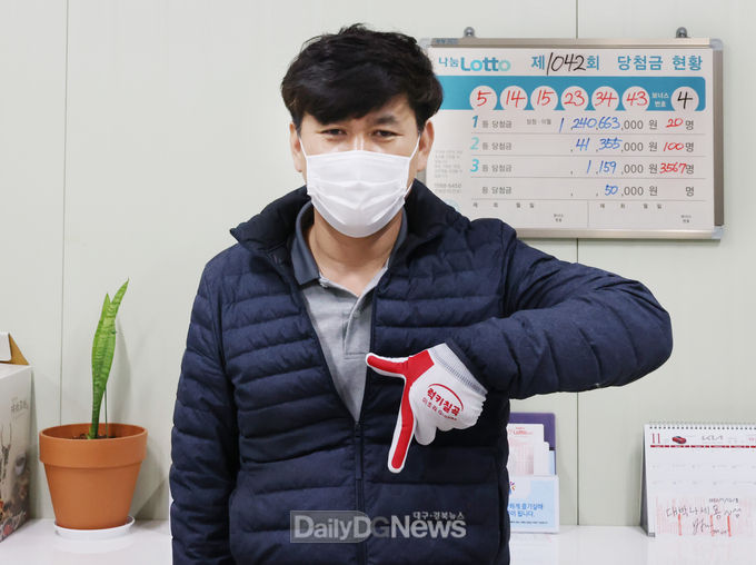 칠곡군 제공) 1등 7장을 판매한 칠곡군 북삼읍의 한 로또복권 사장이 럭키칠곡 포즈를 취하고 있다.