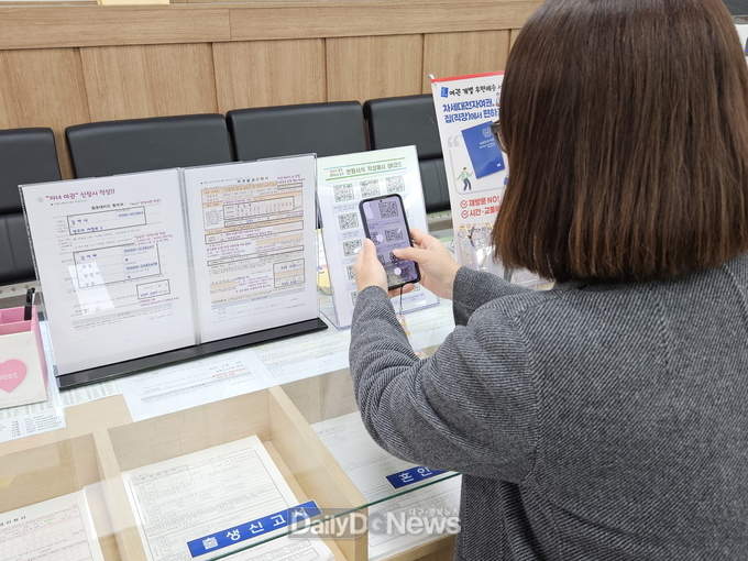 민원인이 시청 민원실에 비치된 민원서식 작성예시 QR코드를 스캔하고 있다