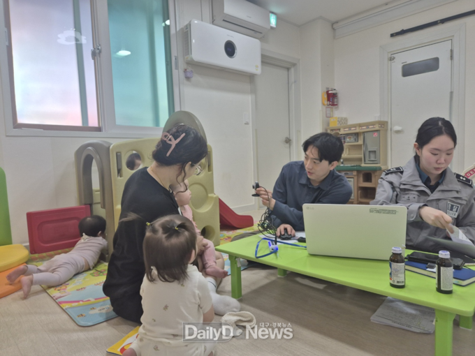 문경경찰서 경찰관들이 문경지역 어린이집을 방문하여 경찰청 실종프로파일링시스템에 등록하기 위하여 영아의 얼굴사진을 촬영하고 있다