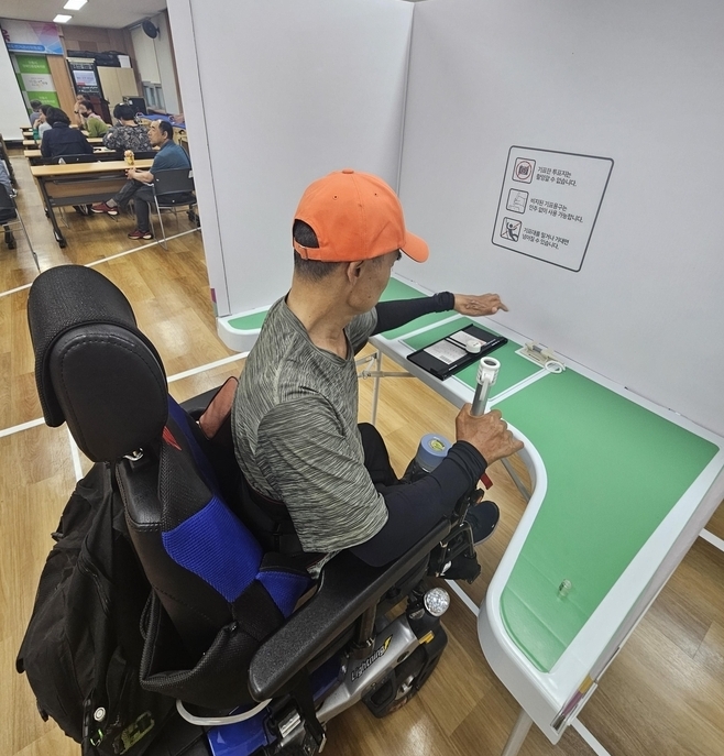 장애인 유권자가 특수형 기표용구를 이용하여 투표체험 하는 장면