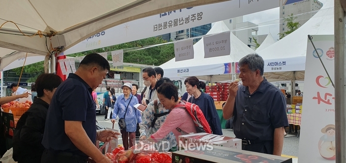서울 강남구청 주차장에서 열린 직거래 장터 영주농산물유통센터 부스에서 사람들이 사과를 시식하고 있다).